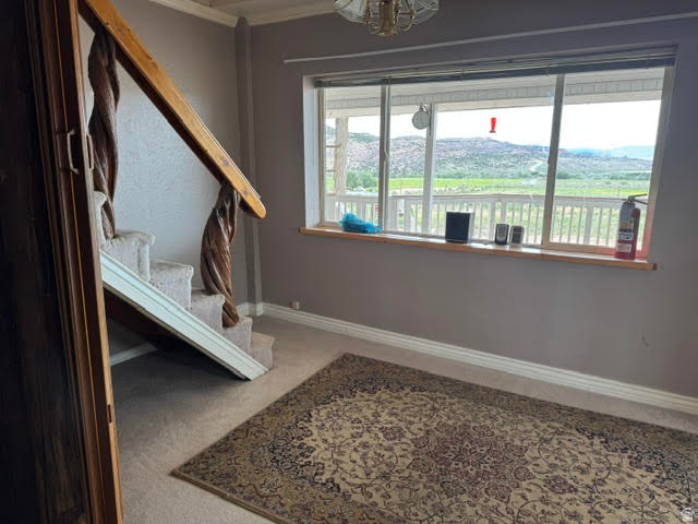 1124 Washam Road Green River, WY 82938 - Photo 29 of 35 Spacious interior featuring a carpeted staircase with a carved wood banister, a large window with a wood sill, and a clear view of the distant mountains and green landscape