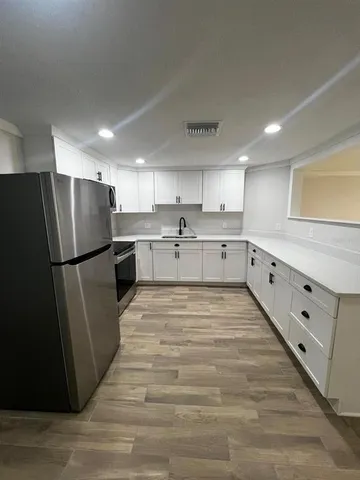a large kitchen with stainless steel appliances a refrigerator and a stove