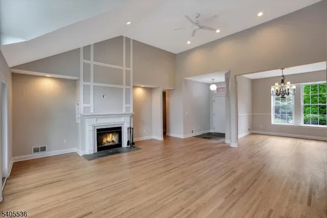 an empty room with wooden floor a fireplace and window
