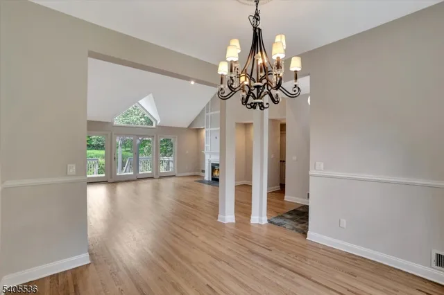 a view of a room with wooden floor chandelier and windows