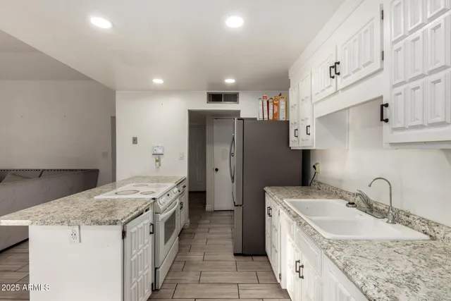 a kitchen with granite countertop a sink stove and refrigerator