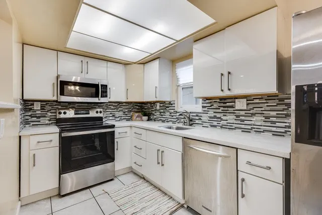 a kitchen with granite countertop white cabinets stainless steel appliances and a counter space