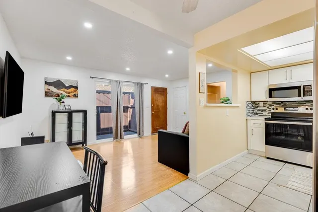 a living room with stainless steel appliances furniture and a flat screen tv