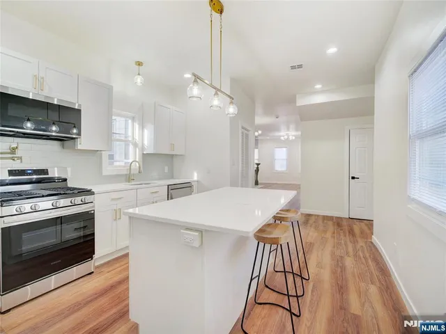 a kitchen with kitchen island a stove a sink and a microwave
