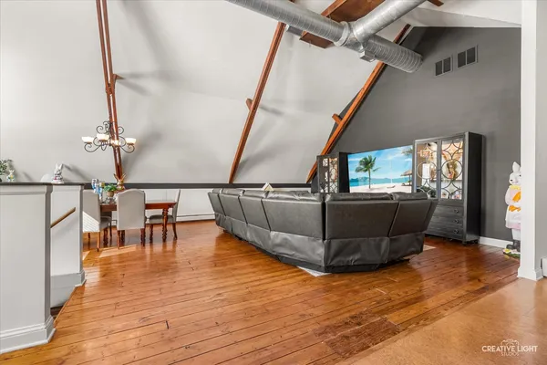 a living room with couches and a dining table with wooden floor