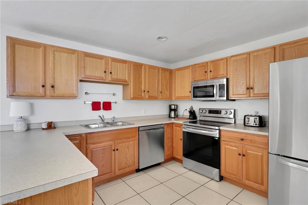 2772 Riverview Drive Naples, FL 34112 - Photo 16 of 23 a kitchen with white cabinets sink and white appliances