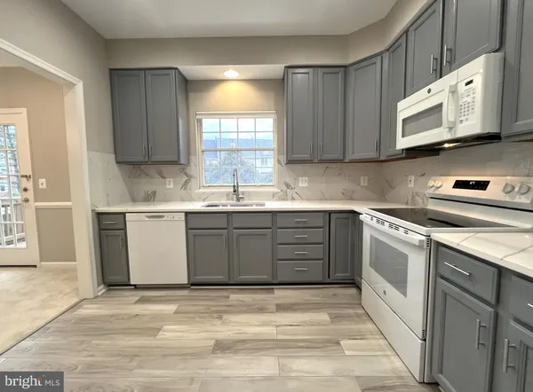 a kitchen with a white refrigerator a sink a stove a microwave and cabinets