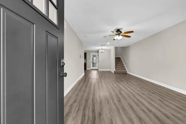 a view of an empty room with wooden floor and a ceiling fan