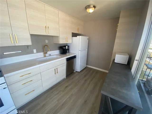 a living room with stainless steel appliances furniture wooden floor and a large window