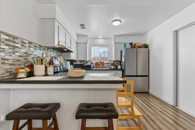 a kitchen with stainless steel appliances a dining table chairs refrigerator and sink