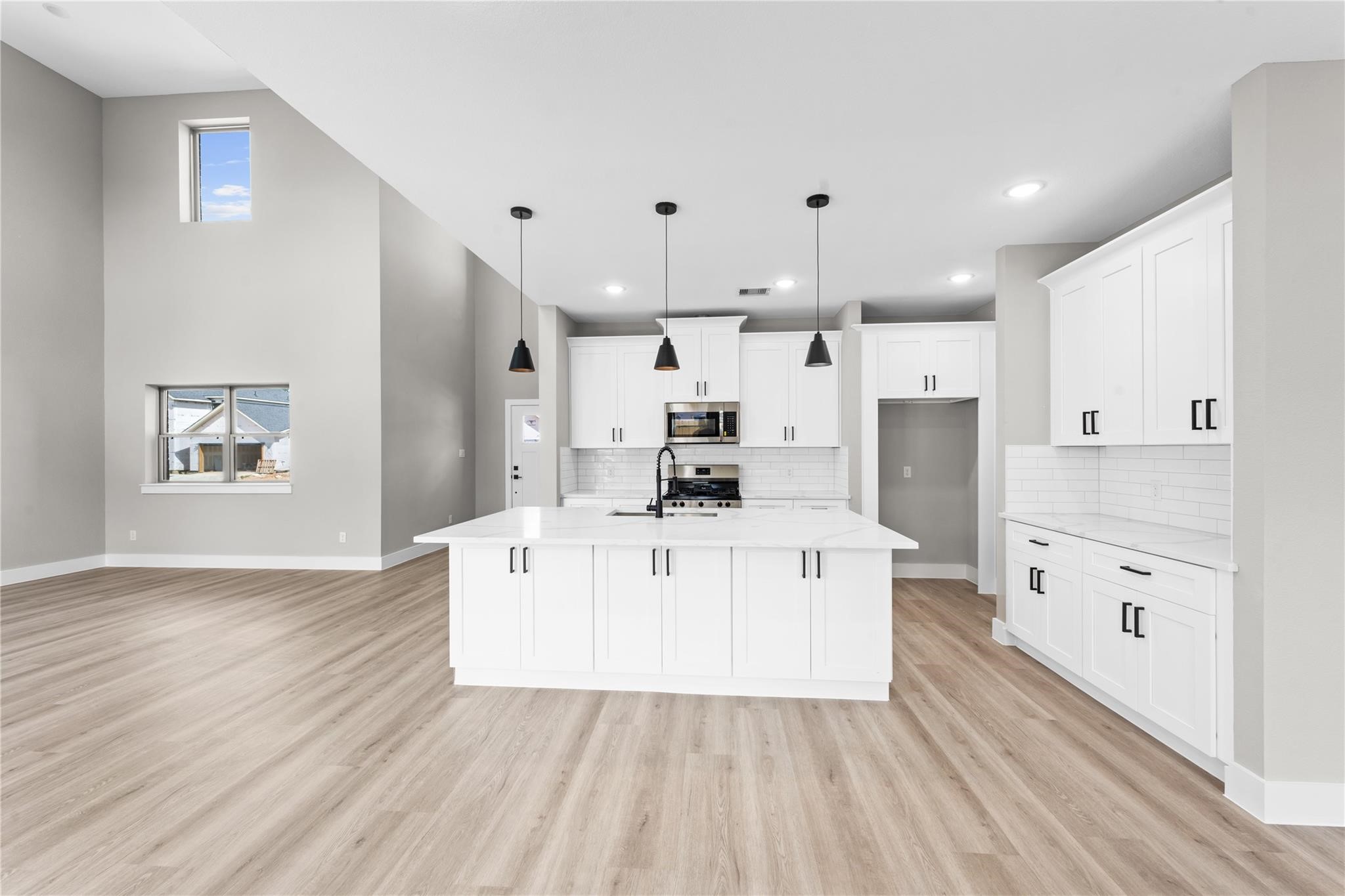 2515 Liguria Spring Spring, TX 77388 - Photo 12 of 15 a large white kitchen with kitchen island a refrigerator a stove a sink dishwasher and white cabinets with wooden floor