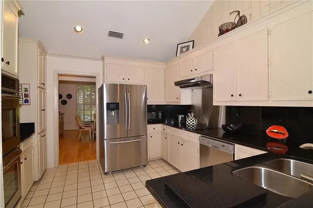 a kitchen with stainless steel appliances granite countertop a refrigerator and a sink