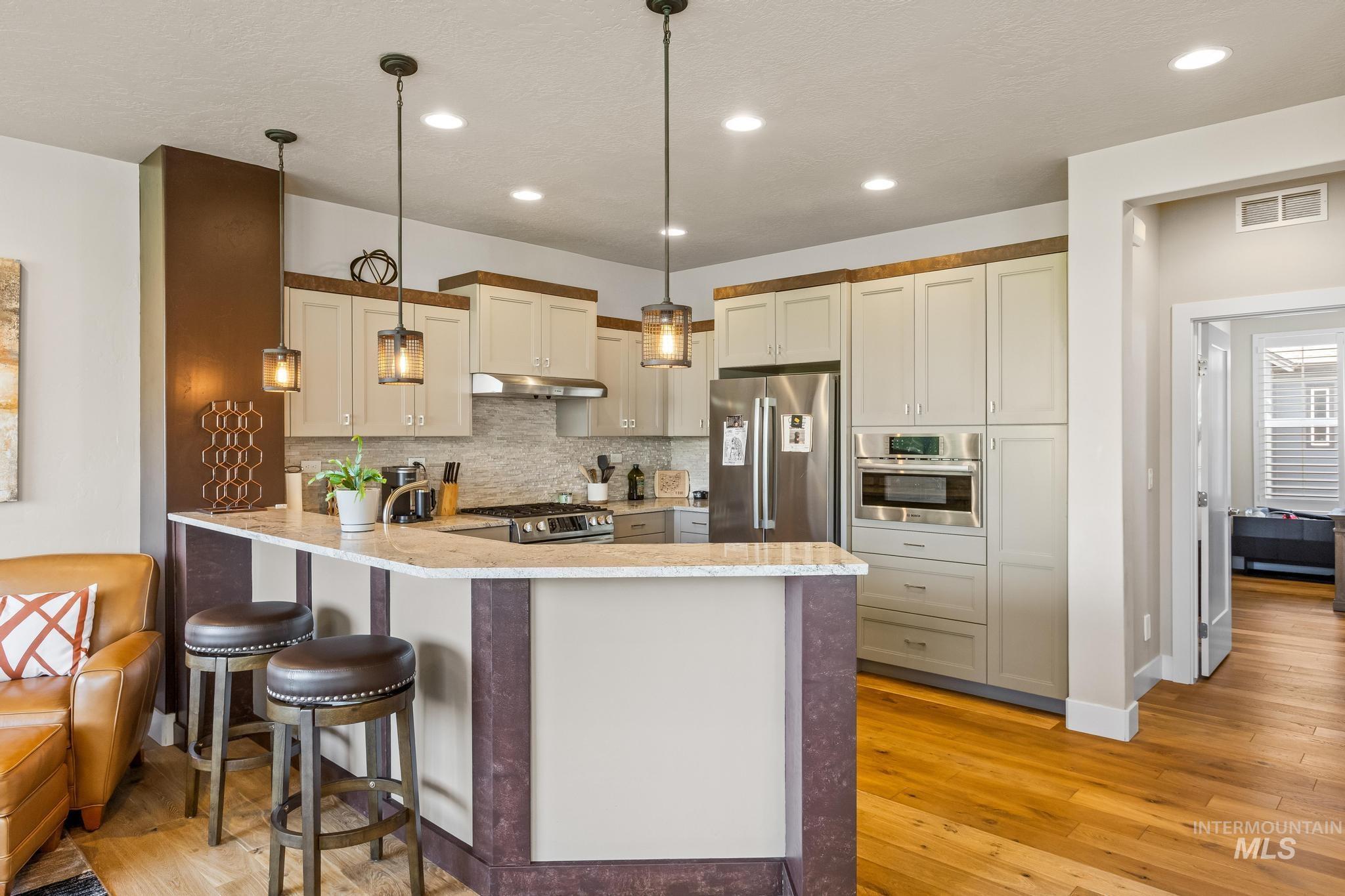 3362 East Exacta Lane Boise, ID 83716 - Photo 18 of 41 Kitchen with backsplash, stainless steel appliances, a peninsula, pendant lighting, and a breakfast bar