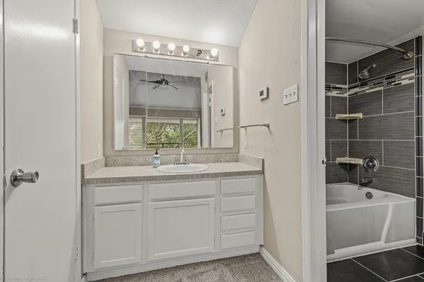 a bathroom with a granite countertop sink a mirror and a bathtub next to a window