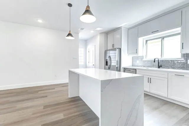 a large kitchen with cabinets wooden floor and a sink