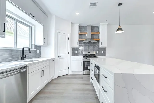 a large kitchen with stainless steel appliances kitchen island granite countertop a sink and cabinets