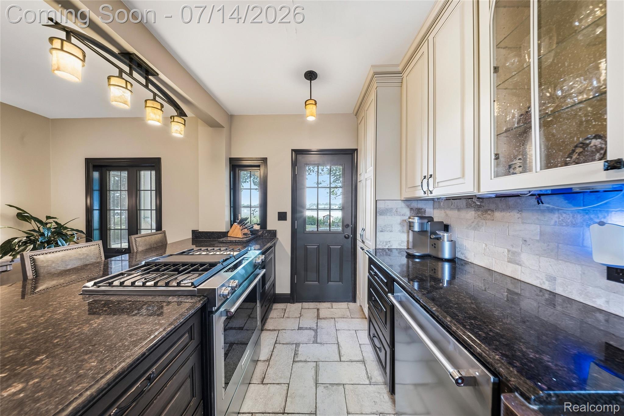 18460 Meridian Road Grosse Ile, MI 48138 - Photo 22 of 50 Kitchen featuring dark cabinetry, light-toned upper cabinets with glass-front accents, and dark stone countertops