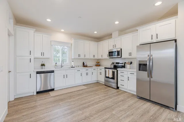 a kitchen with granite countertop white cabinets and stainless steel appliances
