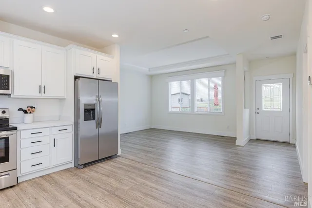 a view of a kitchen with wooden floors and white walls