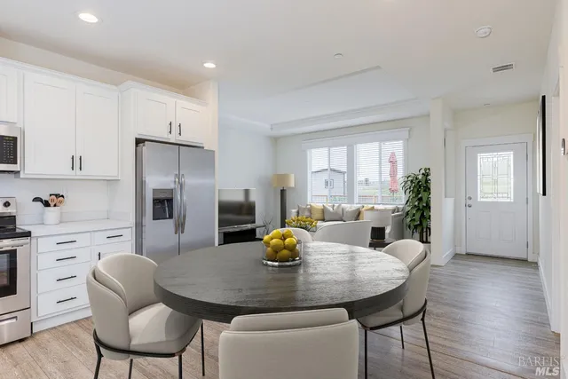 a kitchen with stainless steel appliances a dining table chairs and wooden floor