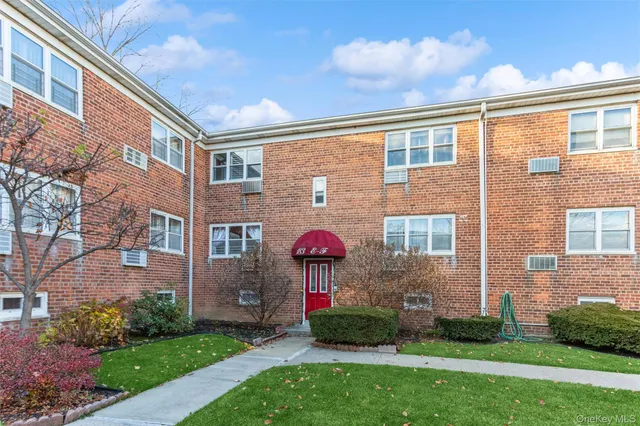 a view of a brick house with a yard and plants