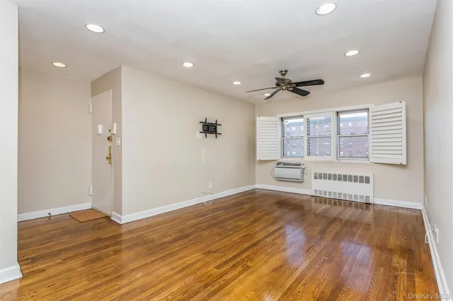 a view of an empty room with a window and wooden floor