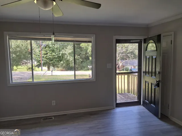 a view of an empty room with wooden floor and a window