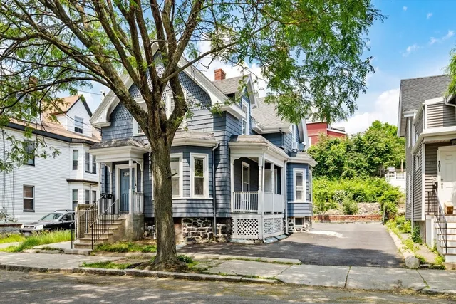 a front view of a building with street view and trees