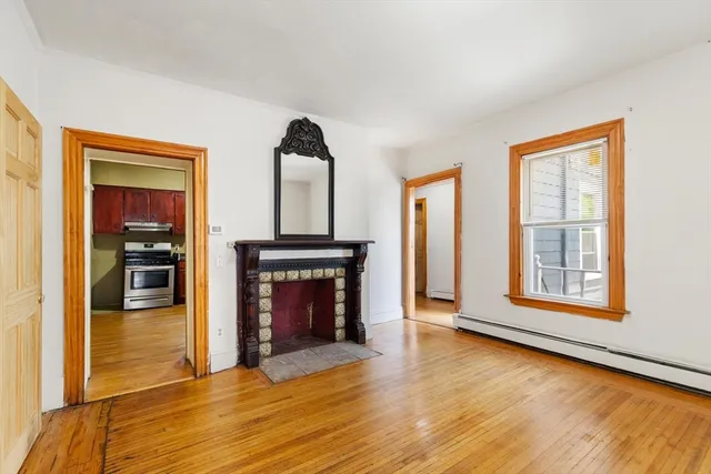 an empty room with wooden floor fireplace and windows