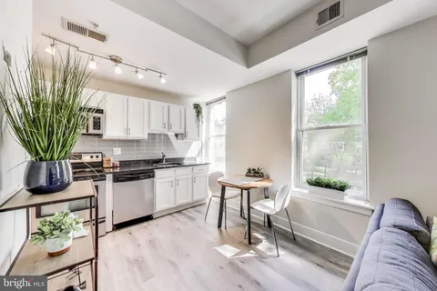 a living room with stainless steel appliances furniture a window and a potted plant