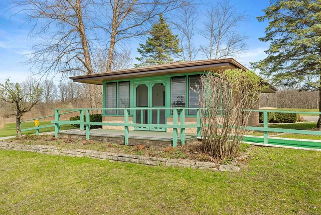 a view of a house with table and chairs under an umbrella