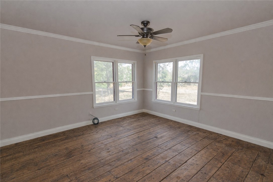 3867 Highway 59 George West, TX 78022 - Photo 19 of 40 an empty room with wooden floor chandelier fan and windows