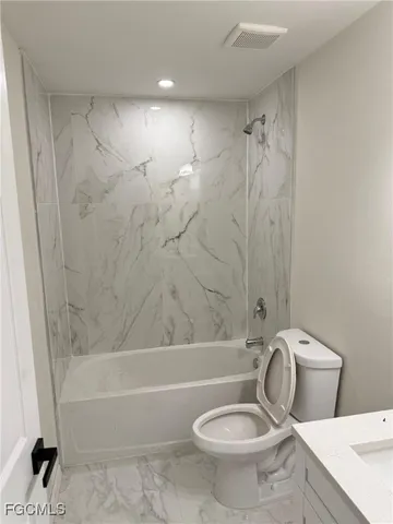 a bathroom with a granite countertop toilet and a shower