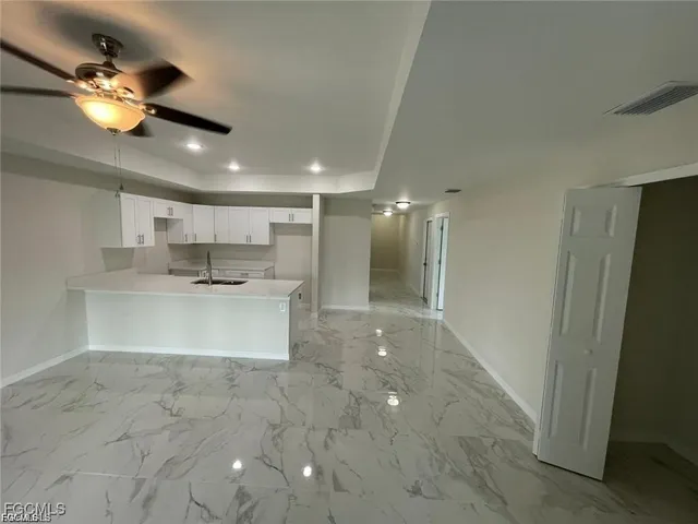 a view of a kitchen with a sink and chandelier fan