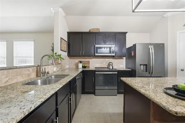 a kitchen with granite countertop a sink stove and refrigerator