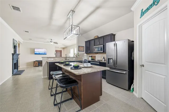 a kitchen with stainless steel appliances kitchen island a table chairs refrigerator and microwave