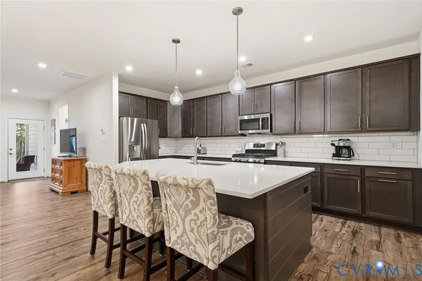 a kitchen with stainless steel appliances granite countertop a sink a stove and a wooden floors
