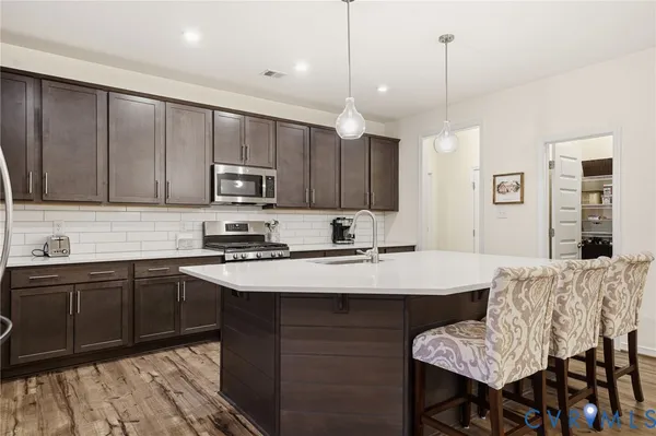 a kitchen with stainless steel appliances a sink dishwasher a refrigerator a stove top oven a refrigerator and cabinets with wooden floor