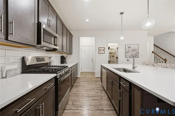 a kitchen with stainless steel appliances a sink a stove a microwave a sink a refrigerator and cabinets
