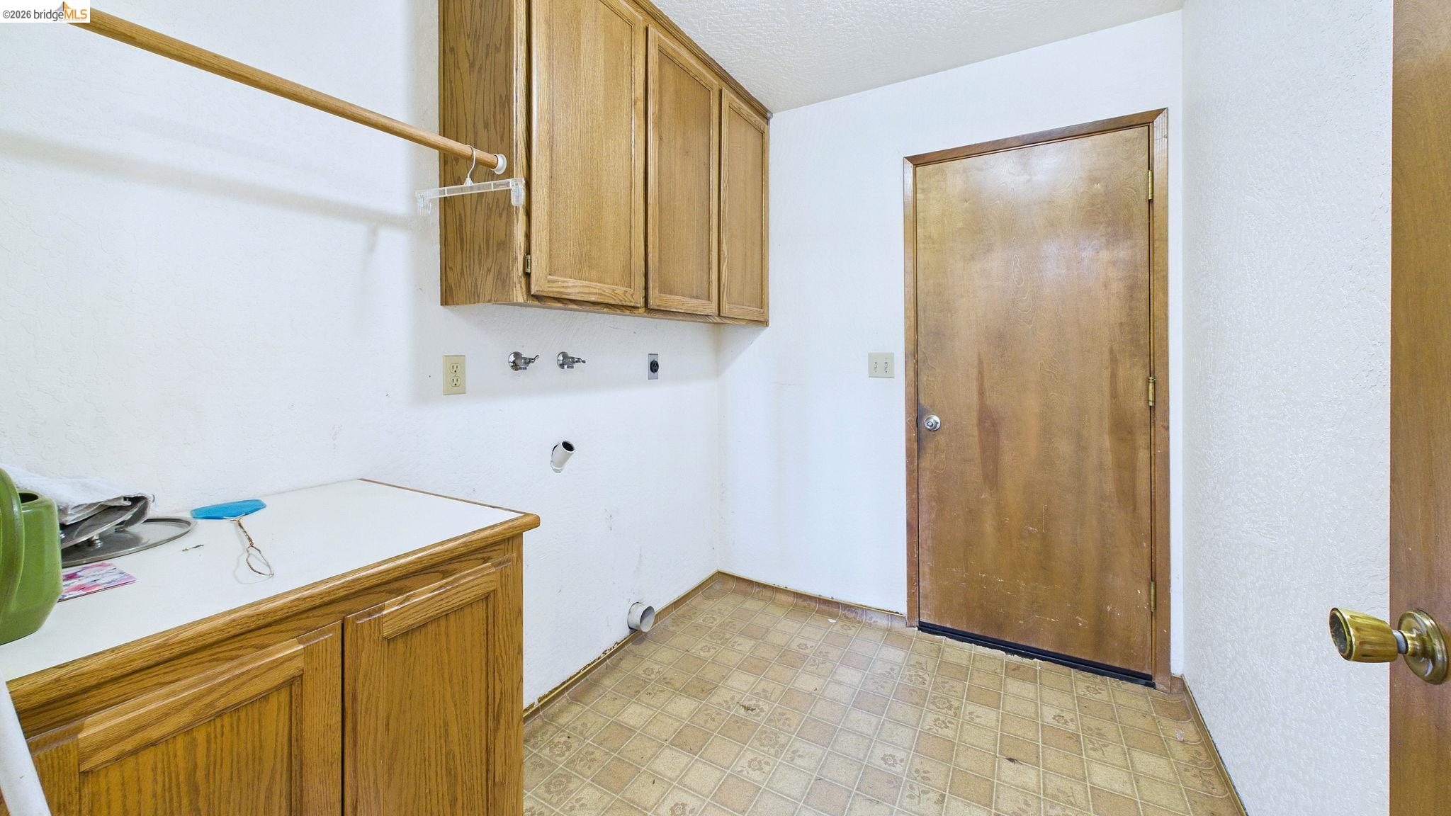 23686 Marble Quarry Road, Unit 72 Columbia, CA 95310 - Photo 32 of 35 Utility space with upper and lower wood-finish cabinetry, a neutral countertop, and a clothes rod