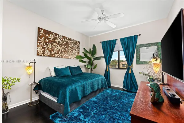 a bedroom with a bed a couch and a flat tv screen on the dresser