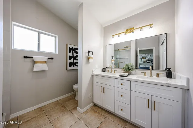 a spacious bathroom with a double vanity sink a mirror and a toilet