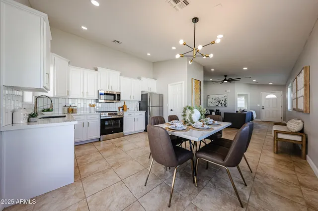 a kitchen with a dining table chairs stainless steel appliances and cabinets