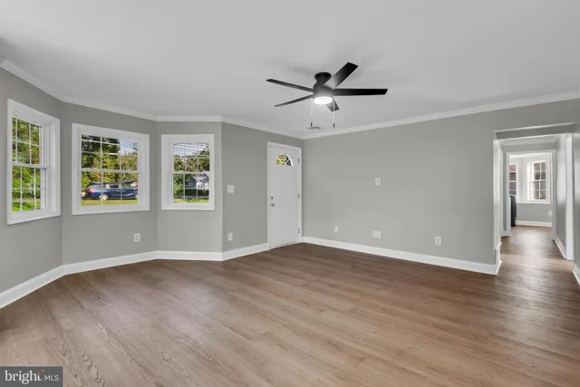 a view of an empty room with wooden floor and a window
