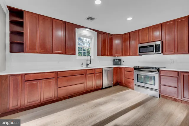 a kitchen with stainless steel appliances granite countertop wooden cabinets a stove top oven a sink and dishwasher