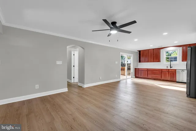 a view of an empty room with wooden floor and a ceiling fan