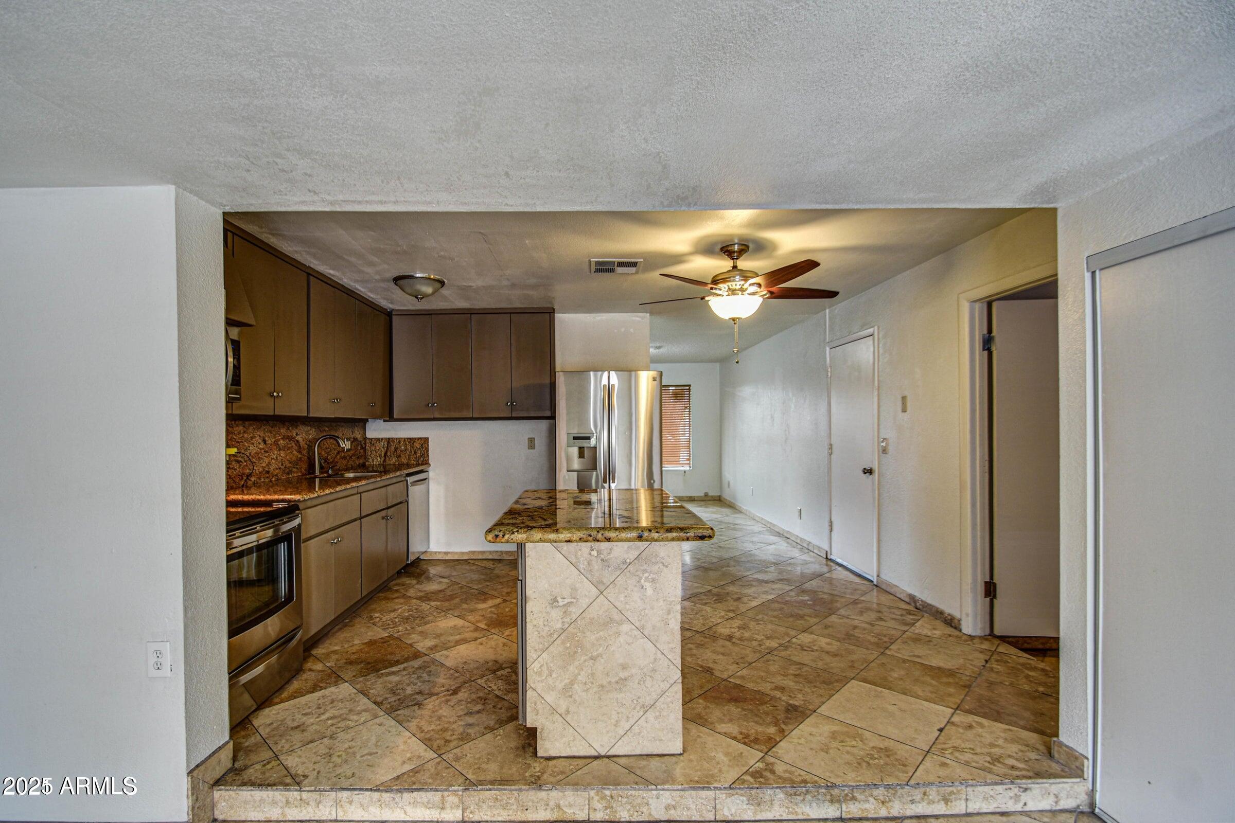17629 North 36th Street Phoenix, AZ 85032 - Photo 9 of 20 a kitchen with kitchen island granite countertop a refrigerator and a stove top oven
