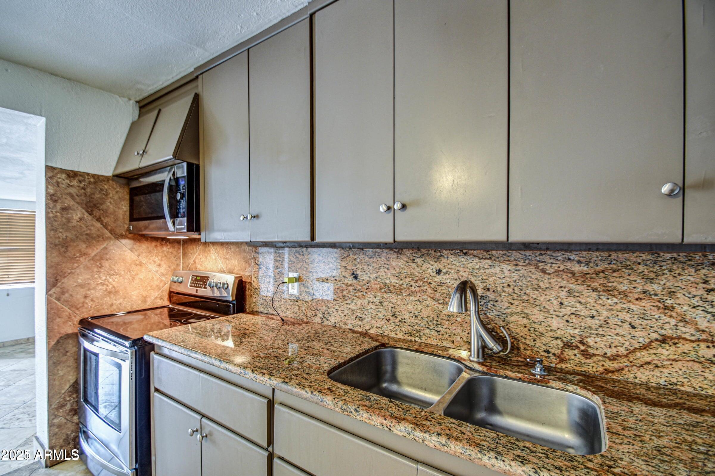 17629 North 36th Street Phoenix, AZ 85032 - Photo 10 of 20 a kitchen with granite countertop a sink and a stove top oven