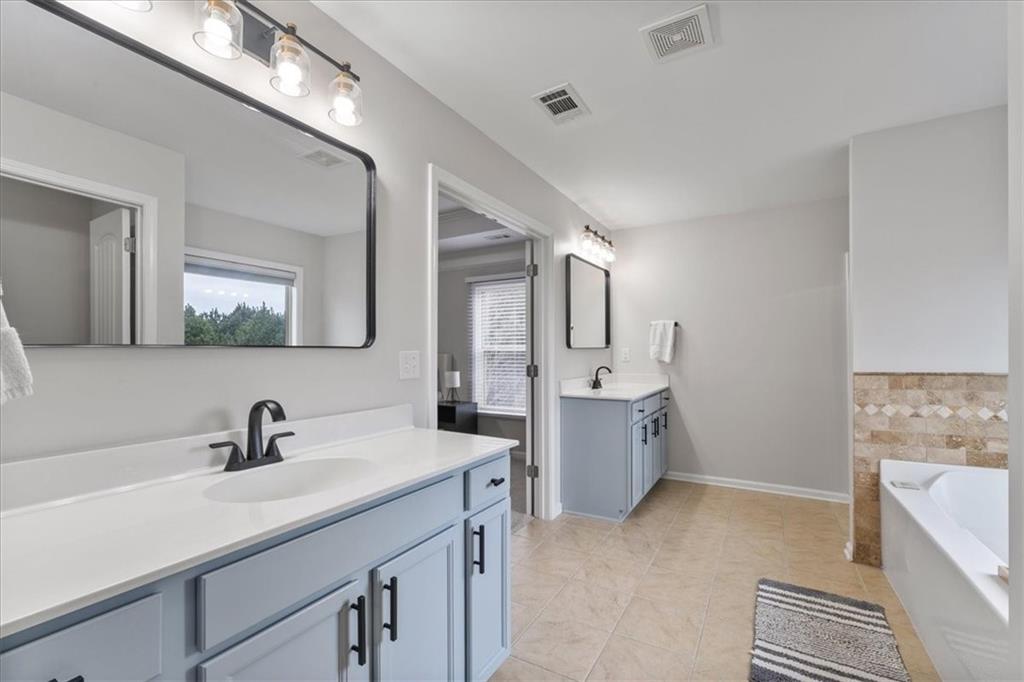 556 Olympic Way Acworth, GA 30102 - Photo 24 of 41 a bathroom with a double vanity sink a mirror and a bathtub