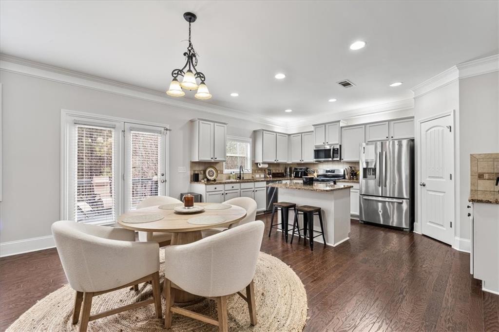 556 Olympic Way Acworth, GA 30102 - Photo 9 of 41 a kitchen with a dining table chairs refrigerator and wooden floor